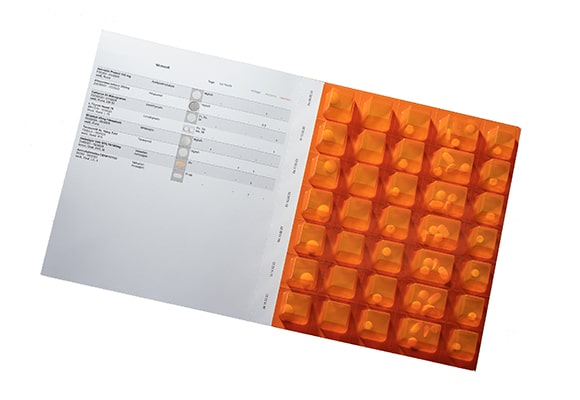 Eine organisierte Medikamentenblisterpackung mit einem aufgedruckten Zeitplan auf der linken Seite und 28 durchsichtigen Fächern, die mit Tabletten gefüllt sind, auf der rechten Seite, entwickelt für die Verwaltung der täglichen Medikamentendosen.