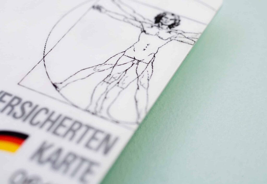 Eine Nahaufnahme einer Karte mit einem Teilbild des Vitruvianischen Menschen von Leonardo da Vinci, deutschem Text über das E-Rezept und einer kleinen deutschen Flagge auf einer hellblauen Fläche - perfekt für Ihre Microsite.